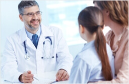 Physician smiling with stethoscope and patient