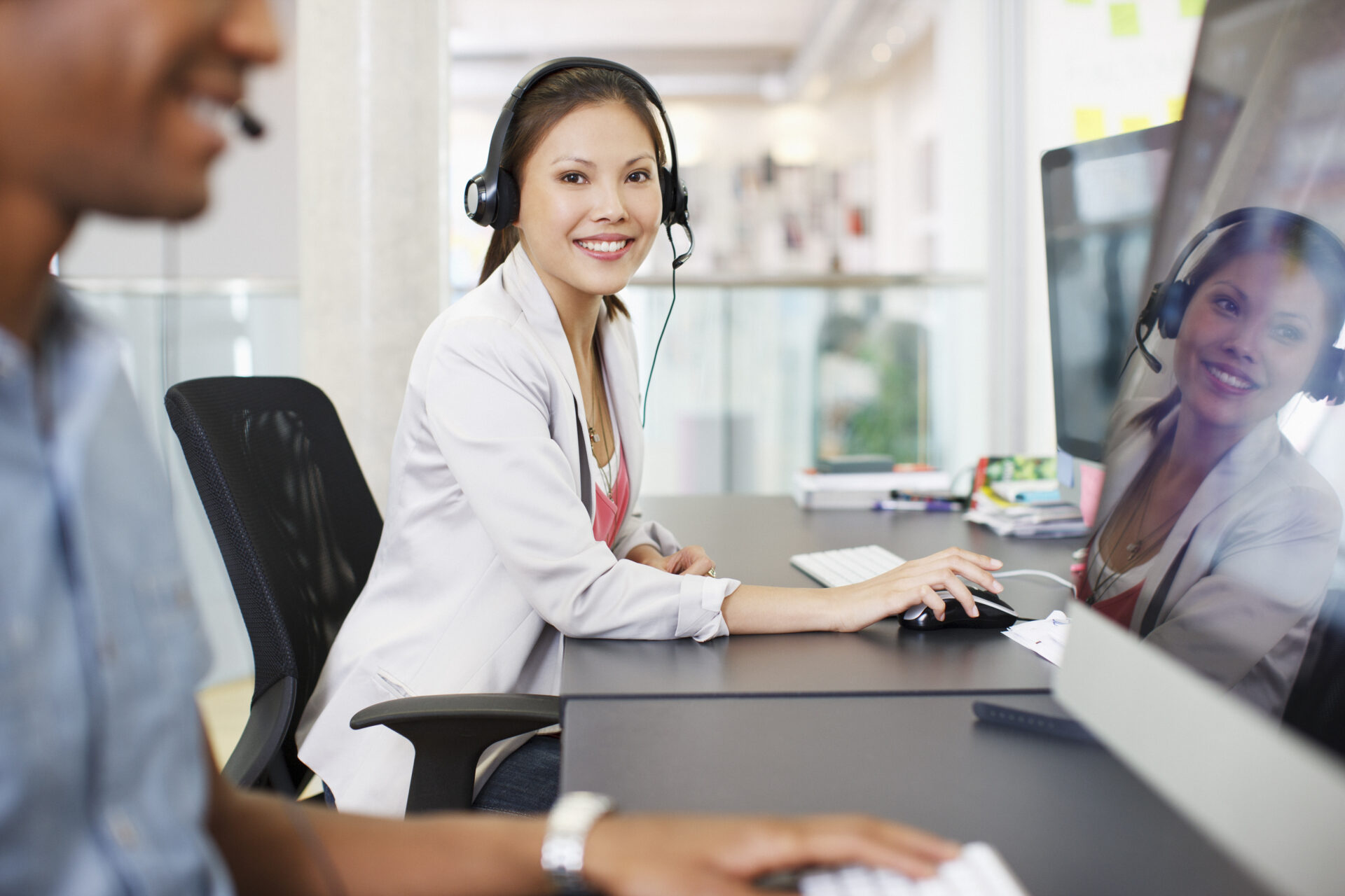 Woman looking at camera smiling in call center wearing headset