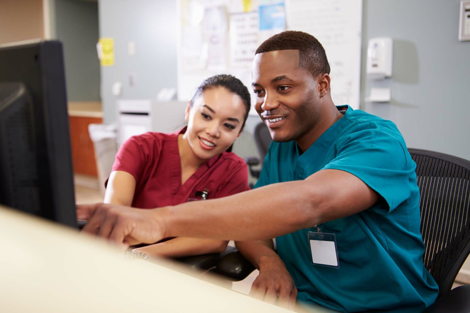 Two people in scrubs looking at monitor